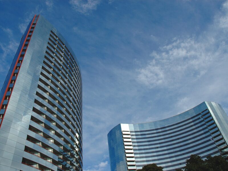 two curved office blocks, blue sky and trees